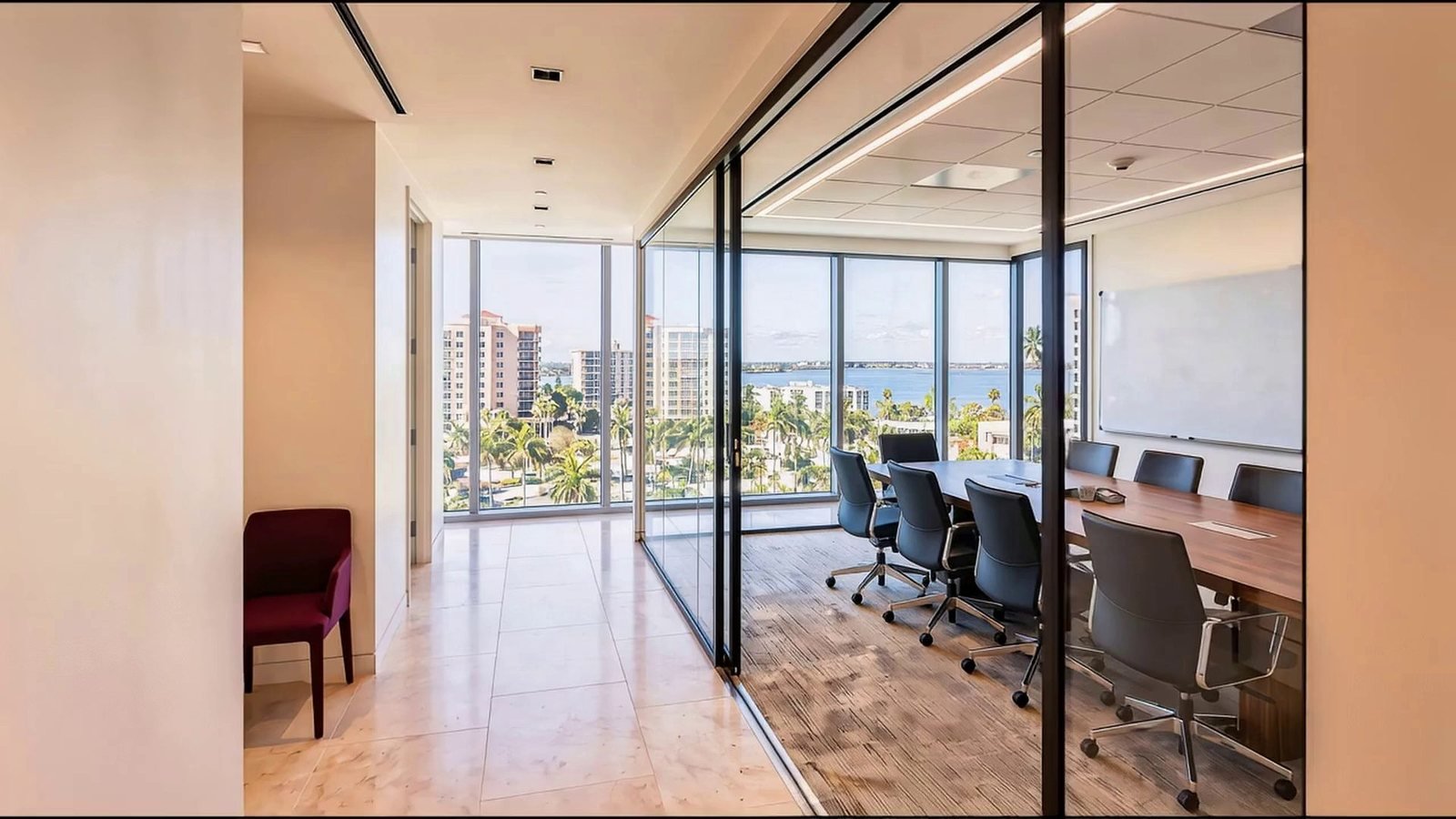 A glass-walled boardroom with an open sliding door, overlooking a waterfront downtown, with a whiteboard on the wall.